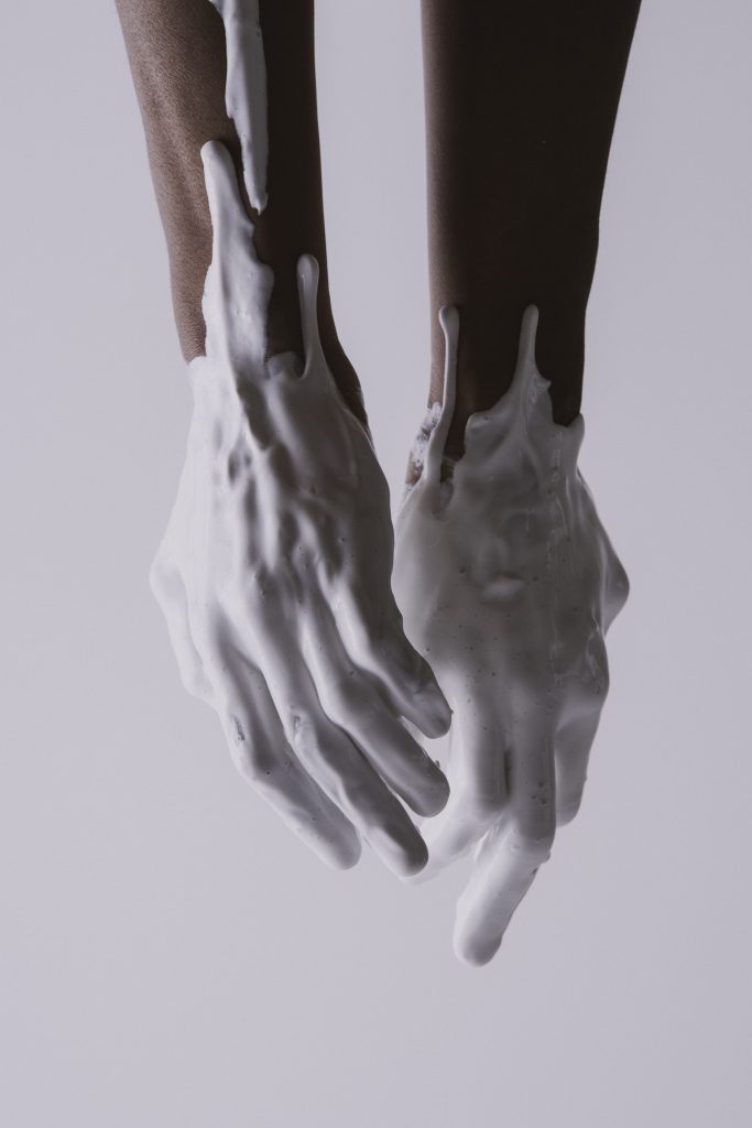 Photo of two hands covered in white acrylic paint.