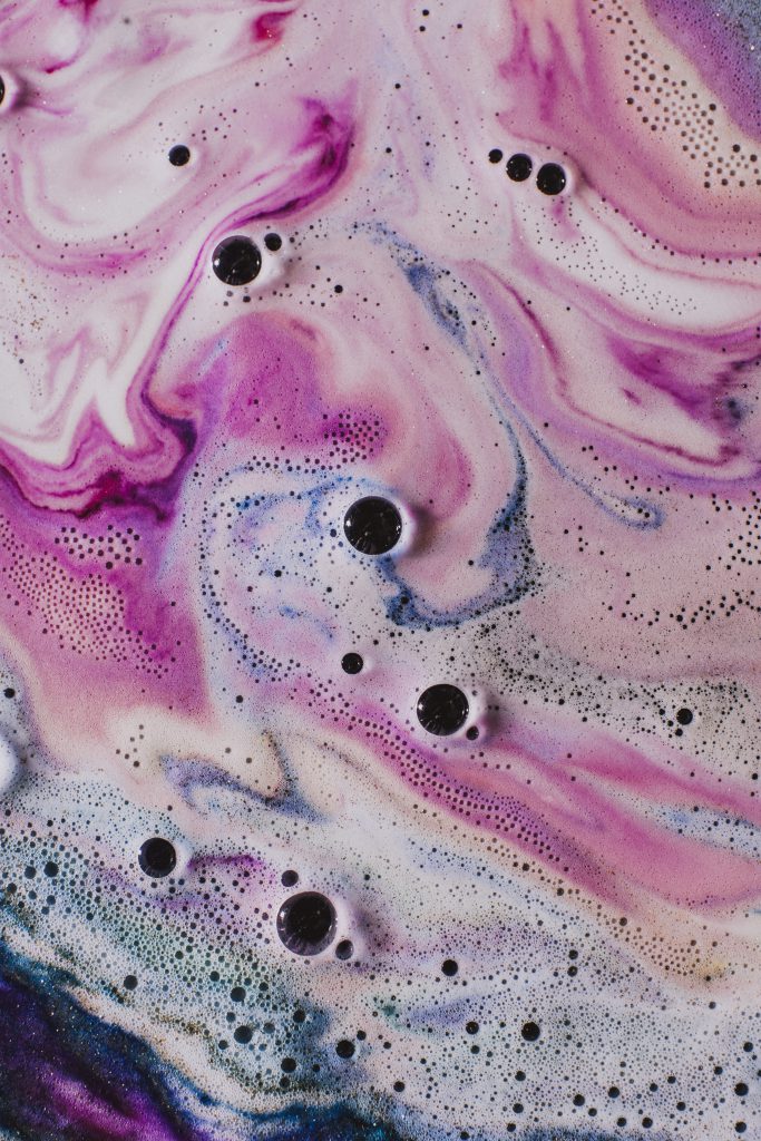 Photo of wet, bubbly, swirling pink and blue paint.